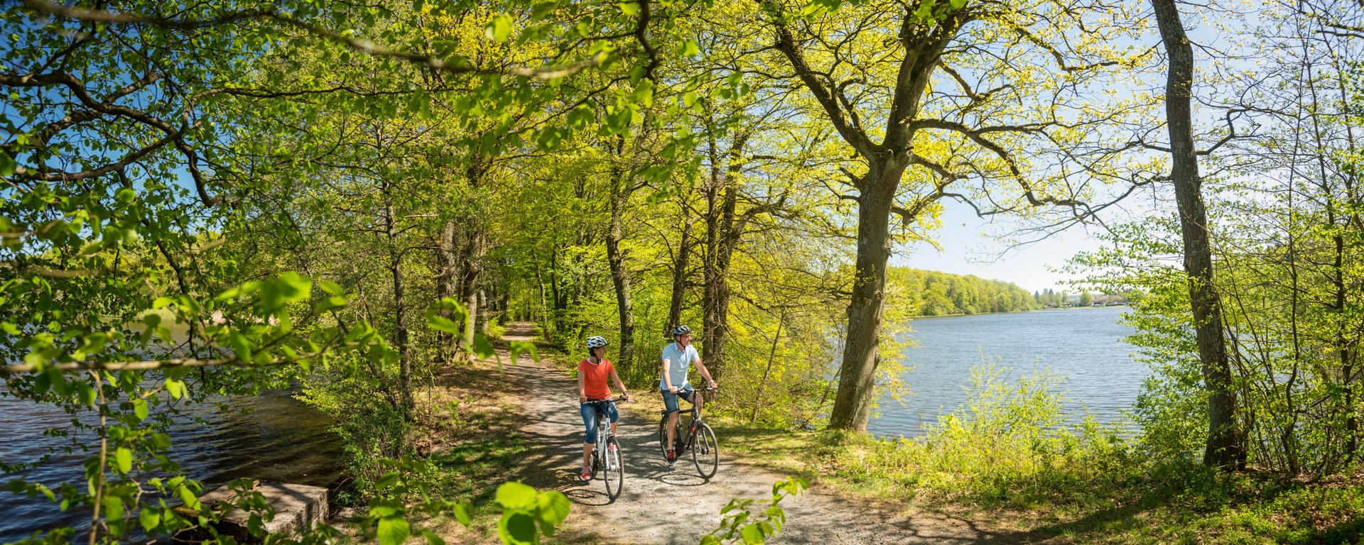 Zwei Radfahrer fahren entlang des Wassers der Westerwälder Seenplatte 