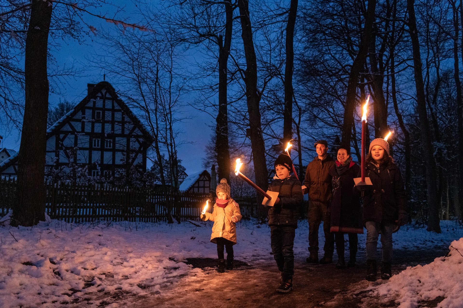 Familie wandert mit Fackeln durch den Burggarten 