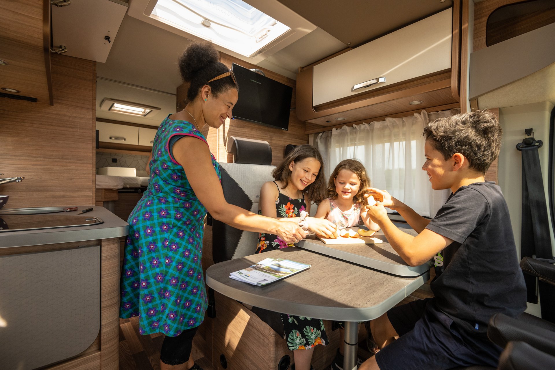 Mutter mit drei Kindern bereitet Essen im Camper vor